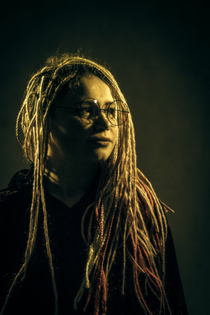 Girl in glasses with dreadlocks over dark backgroundの写真素材