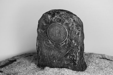 Tombstone with bitcoin symbol in green grass over gray backgroundの写真素材
