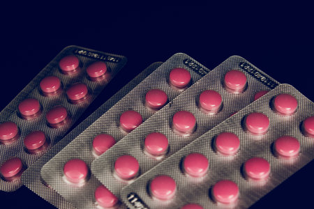 Red pills in blister packs over black background