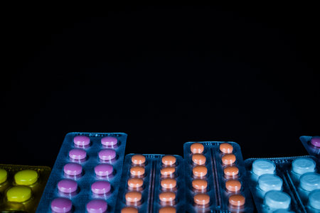 Red and orange pills in blister packs over black backgroundの写真素材