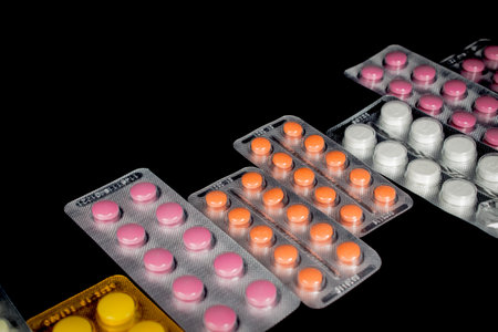 Red and orange pills in blister packs over black background