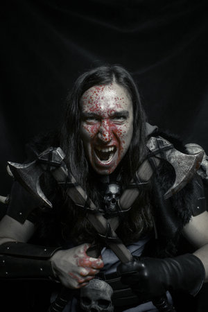 Northern warrior with war axes posing over dark background