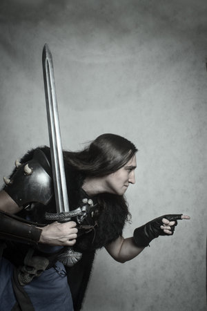 Northern warrior in sword and posing over grey background