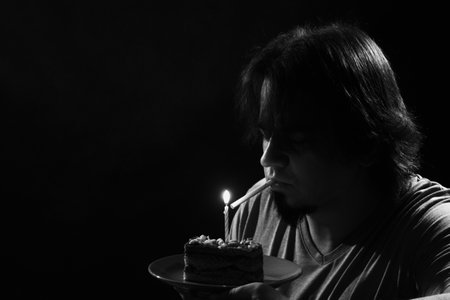 Adult man with birthday cake over dark background.の写真素材