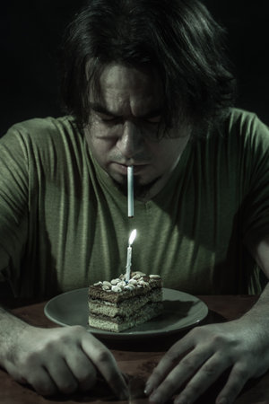 Adult man with birthday cake over dark background.の写真素材