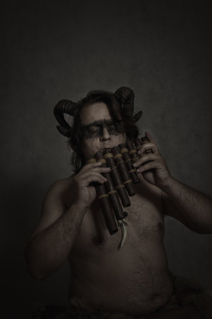 Horned faun posing with wooden panfluteの写真素材