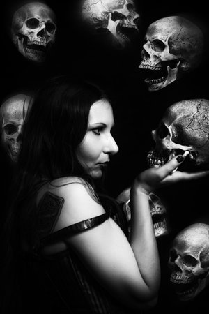 Gothic girl in red corset summoning horde of skullsの写真素材