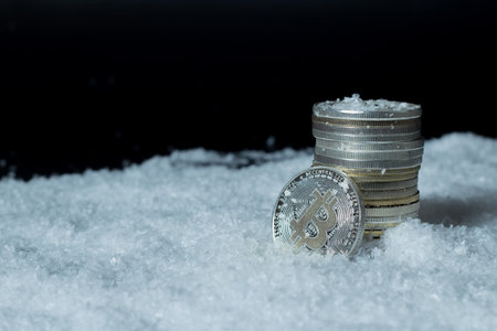 Close-up of stack of bitcoins on glittering snow. Electronic money concept.