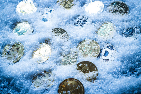 Close-up of cryptocurrency coins on glittering snow. Electronic money concept.