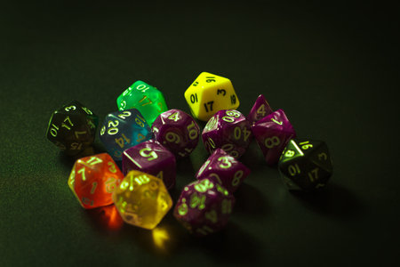 A dramatic close-up of colorful polyhedral dice used in tabletop role-playing games, placed on a dark surface.の写真素材