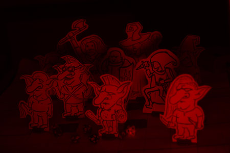 Hand-drawn fantasy tabletop role-playing game scene with paper miniatures of goblins and adventurers, including a wizard, paladin, warrior, and rogue. The figures are placed on a grid battle map with d20 scattered around, creating a vivid and creative RPG atmosphere.の写真素材