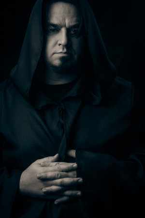 Dark moody portrait of a mysterious hooded man emerging from shadows. Low-key cinematic lighting...