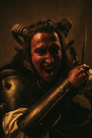 A dramatic fantasy portrait of a fierce red-skinned tiefling rogue wielding a dagger, captured in a dark, cinematic atmosphere. The character features curved horns, intense expression, and medieval-style armor, embodying a stealthy assassin or warrior archetype from role-playing games. Warm, moody lighting enhances the sense of danger, power, and mystery, making this image perfect for fantasy concepts, RPG themes, dark storytelling, and epic character design.の写真素材