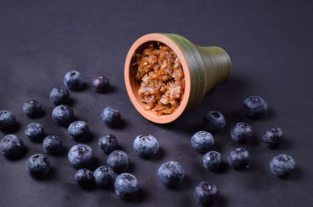 hookah bowl with tobacco on an black background with blueberriesの写真素材