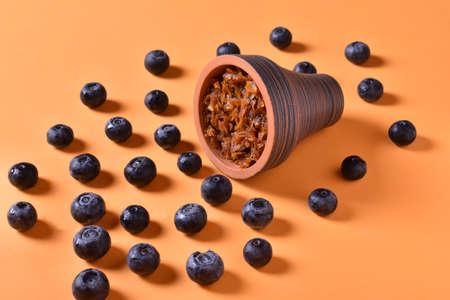 hookah bowl with tobacco on an orange background with blueberriesの写真素材