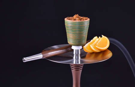 hookah bowl with tobacco on an black background with orangeの写真素材