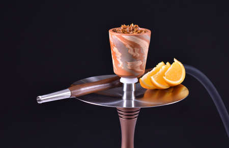 hookah bowl with tobacco on an black background with orangeの写真素材