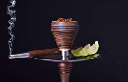 hookah bowl with tobacco on an black background with lime