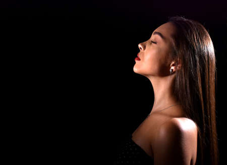 beautiful young woman with luxurious makeup and bare shoulders. Black background with space for textの写真素材