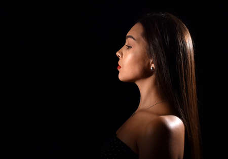 beautiful young woman with luxurious makeup and bare shoulders. Black background with space for textの写真素材