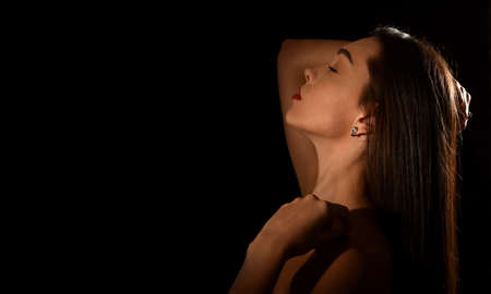 beautiful young woman with luxurious makeup and bare shoulders. Black background with space for textの写真素材