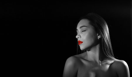 portrait of a beautiful young woman with closed eyes and bare shoulders, isolated on black background with space for text.monochromeの写真素材