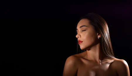 portrait of a beautiful young woman with closed eyes and bare shoulders, isolated on black background with space for textの写真素材