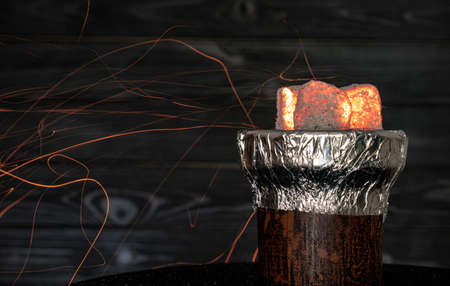 hot burning red coals for a hookah with sparks on a dark background.Traditional Asian relaxation. Space for textの写真素材