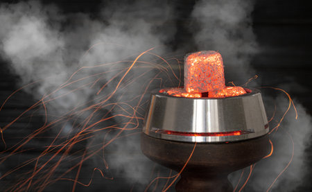 hot burning red coals for a hookah with sparks on a dark background.Traditional Asian relaxation. Space for textの写真素材