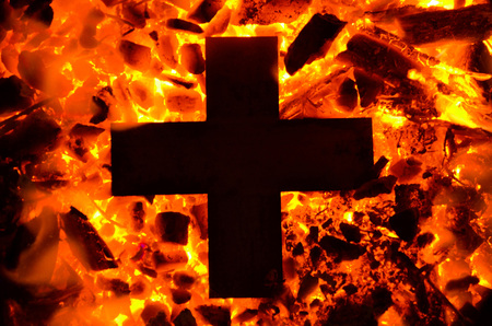 The metal cross begins to heat up on hot coals.の写真素材