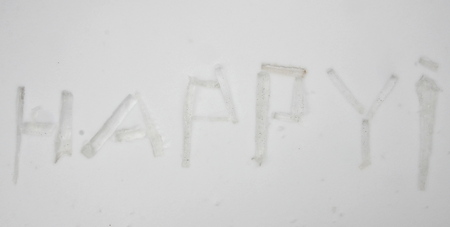The word happy with an exclamation mark is made from the fragments of icicles folded on the snow.の写真素材