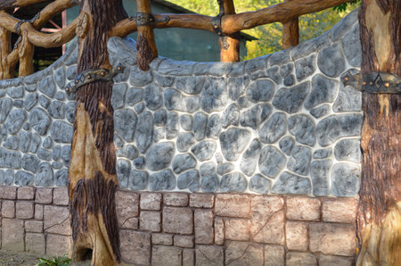 Decorative fence made of rubble stone, blocks and pillars of thick wood.の写真素材