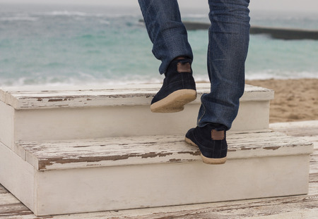 Man's foot walking up on wooden ladder. Sea on backgroundの写真素材