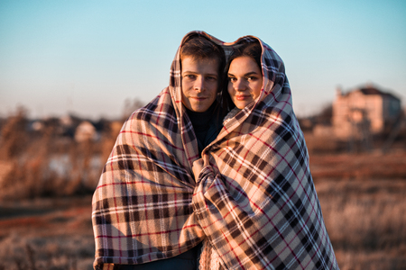 Young and beautiful ukrainian couple is wrapped with the heart shaped plaid, outdoors shoot.の写真素材