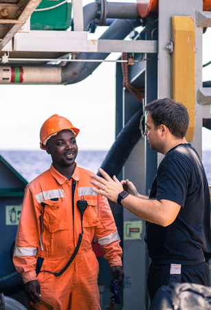 friendship of nations on board of ship/vessel. European Chief officer instructing African seaman on...