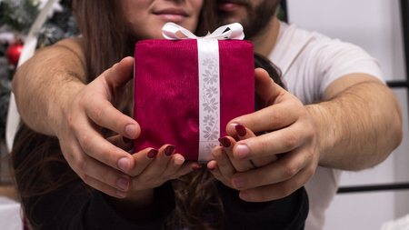 Hands of couple giving a red Christmas giftの写真素材