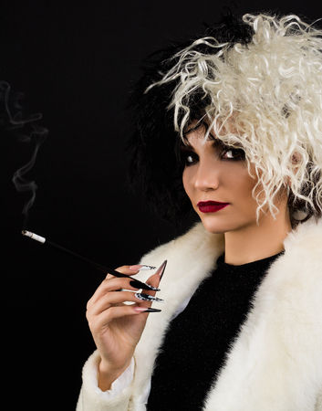 woman dressed up as Cruella halloween character, Black and white  colors . She has cigarette holder in her hand.の写真素材