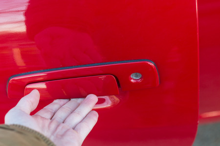 Male hand opening the door handle of red carの写真素材