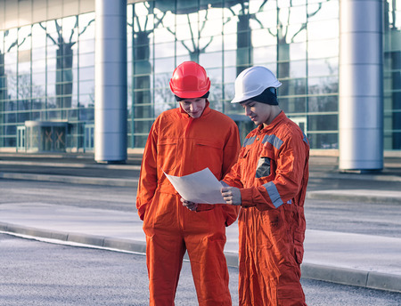 team of  young engineers discussing a construction project. The wear overalls and safety helmets. Business modern backgroundの写真素材