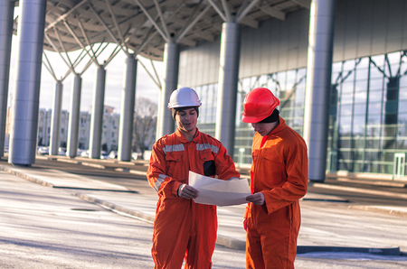 team of  young engineers discussing a construction project. The wear overalls and safety helmets. Business modern backgroundの写真素材