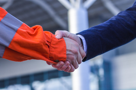 businessman handshaking with worker. Handshake of suit and boilersuit. Business modern background
の写真素材