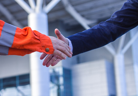 businessman handshaking with worker. Moment before handshake of suit and boilersuit. Business modern backgroundの写真素材