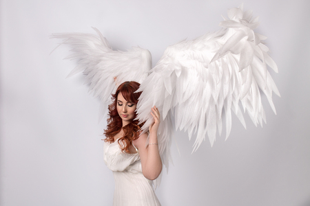 beautiful young model with open angel wings  with pink on white backgroundの写真素材