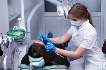 Dentist at work examining woman's teeth in dental clinicの写真素材