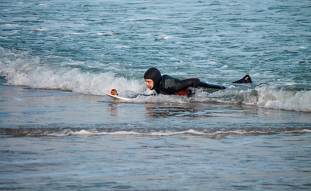 Surfer is shooting himself in the water with surfboard. Selfie in water