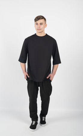 Young muscular guy wearing black clothes and sneakers isolated on white backgroundの写真素材