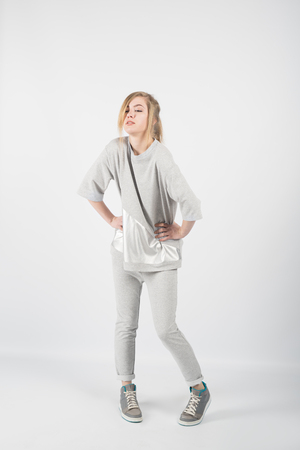 Young beautiful girl wearing grey clothes and sneakers isolated on white backgroundの写真素材