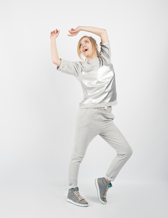 Young beautiful girl wearing grey clothes and sneakers posing isolated on white background. Hands up and looking upの写真素材