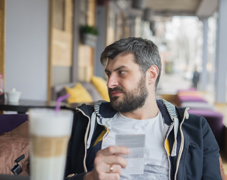 Disappointed man received big bill in cafe or restaurant. He needs to pay too much money. Payment exceeded expectations.の写真素材