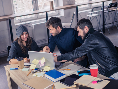 Young smart team. Group of  modern people discussing project on meeting in the office. Working environment with laptop, coffee, notepads and stationery.の写真素材